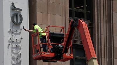 A worker takes a smartphone photo as a Twitter sign comes down at the social media company's headquarters building in San Francisco as part of a rebranding. Reuters