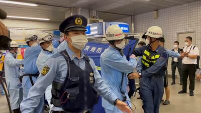 Police escort rescue workers carrying a person through a train station following a knife attack on a train in Tokyo, Japan. Reuters