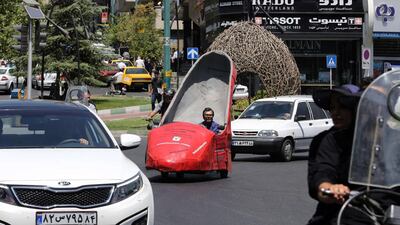 Whether they are on foot, in a car or motorcycle, people stop to clamour for selfies both in and outside the three-wheeled fibreglass stiletto. Atta Kenare / AFP