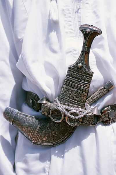 A ceremonial Omani khanjar is worn tucked into a silver belt over a white dishdasha. Getty Images