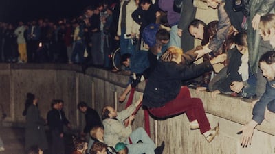 East Berliners get helping hands from West Berliners as they climb the Berlin Wall. AP Photo