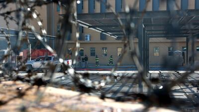 US embassy staff and guards are seen through the barbed wire fence as members of the Popular Mobilisation Forces and their supporters attack the entrance of the US embassy in Baghdad. EPA