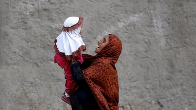A mother plays with her baby, as they are heading to a nearby bus stop early cold morning in Karachi, Pakistan. Reuters