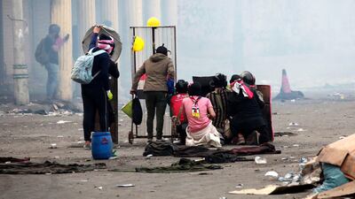 Iraqi protesters take cover during clashes with anti-riot police forces at the Al Rasheed street in central Baghdad. EPA