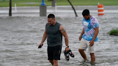 Jesse Perez and Sergio Hijuelo walk through flooded streets near Lake Pontchartrain. AP