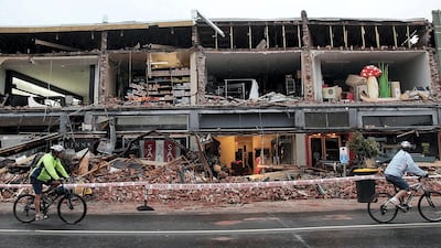 Cyclists riding past a damaged building in the Redcliffs suburb of Christchurch on February 23, 2011, a day after a deadly 6.3 magnitude earthquake rocked the city. AFP