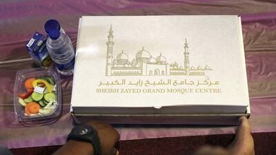 A visitor waits with a food box on the first day of Ramadan at the Sheikh Zayed Grand Mosque in Abu Dhabi. Pawan Singh / The National