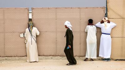 Abu Dhabi, United Arab Emirates, December 11, 2019. Camel fans take a sneak peek on gaps on the fence at the Al Dhafra Camel Festival 2019. Victor Besa/The National Section: NA Reporter: Anna Zacharias