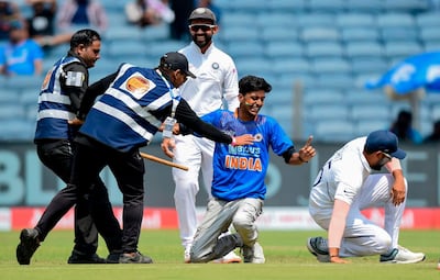 Security guards detain a fan after he entered the ground to meet Rohit Sharma. AFP