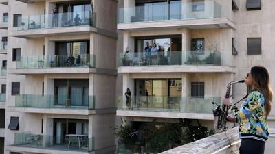 This picture taken on March 23, 2020 shows saxophonist Yarden Klayman performing on a rooftop for residents of Basel Square in Tel Aviv after her concert was cancelled due to the COVID-19 novel coronavirus. / AFP / Jack GUEZ