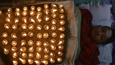 A Nepalese Hindu devotee lies in a bed covered by 108 lit oil lamps on the tenth day of Dashain (Durga Puja), in Bhaktapur on the outskirts of Kathmandu on October 11, 2016. Dashain is the longest and the most auspicious festival in the Nepalese calendar and celebrates the triumph of good over evil. / AFP / PRAKASH MATHEMA