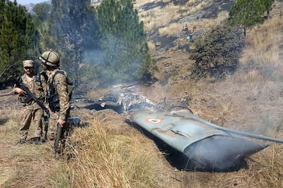 Pakistani soldiers stand next to what Pakistan says is the wreckage of an Indian fighter jet shot down in Pakistan controlled Kashmir. AFP