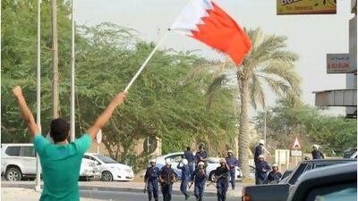 A protester waves the Bahraini flag as anti-riot police storm Duraz village, north of Manama, yesterday. Most of Bahrain's Shiite villages and parts of Manama saw marches just hours after martial laws was lifted. Mazen Mahdi / EPA