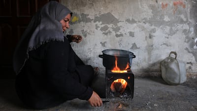 A Palestinian woman prepares food on a fire inside her damaged home, at Shati refugee camp in Gaza city. Reuters