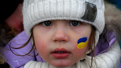 Zlata, 3, with her face painted in the colours of the Ukrainian flag, stands on the Romanian side of the border with Ukraine after fleeing the country. AP