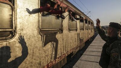 Migrants wave after boarding a train near the southern Macedonian town of Gevgelija. Greek riot police struggled to maintain order after clashes between asylum-seekers at the country’s border with Macedonia. Visar Kryeziu / AP photo