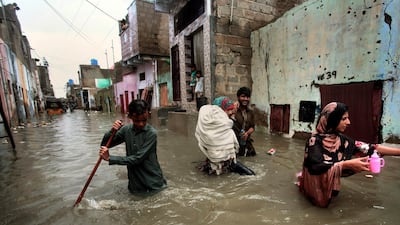 A family wades through a flooded street caused by heavy monsoon rains, in Karachi, Pakistan. Monsoon rains have inundated much of Pakistan, leaving large parts of the southern city of Karachi underwater and causing some deaths. AP