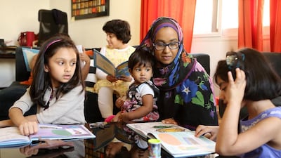 Sadia Anwar, centre, founder of the Dubai group Bismillah Babies, helps children to read the book, My Ramadan Journal – Around the World. Pawan Singh / The National