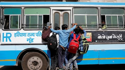 Migrant workers hang on to a door of their moving bus as they return to their villages, during a 21-day nationwide lockdown to limit the spreading of coronavirus disease (COVID-19), in Ghaziabad, on the outskirts of New Delhi. REUTERS