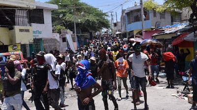 People follow armed gang members in a march organised by former police officer Jimmy 'Barbecue' Cherizier, leader of an alliance of armed groups, in the Delmas neighbourhood