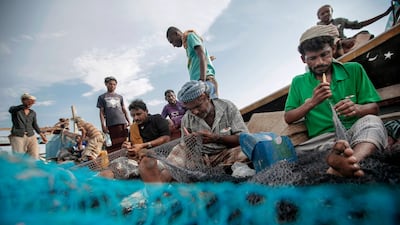 In this Sept. 29, 2018, photo, fishermen work on their nets before a fishing trip at the main fishing port, in Hodeida, Yemen. (AP Photo/Hani Mohammed)