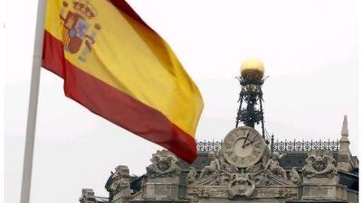 A Spanish flag flies near the dome of the Bank of Spain in central Madrid.