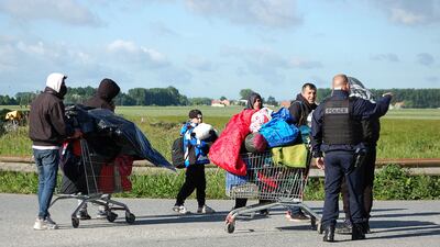 A police officer points to a direction as migrants from Afghanistan walk with belongings during the evacuation of a migrant camp in Grande-Synthe, northern France. AFP