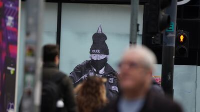 Passersby view a mural by street artist Foka Wolf of UK Prime Minister Boris Johnson dressed as a policeman wearing a festive hat, in Manchester, on Friday. PA