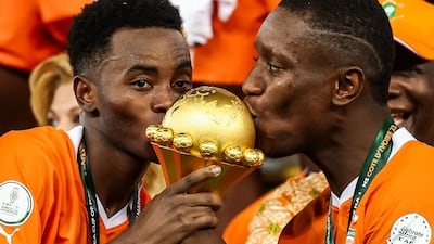 Ivory Coast forward Max-Alain Gradel, right, and teammate Simon Adingra kiss the Africa Cup of Nations trophy on the podium. AFP