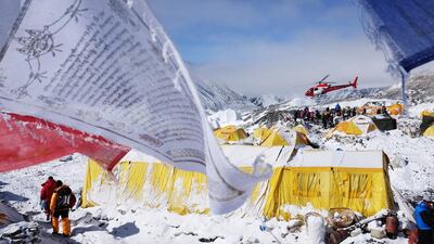 In this photograph taken on April 26, 2015, Buddhst prayer flags flutter in the wind near tents as a rescue helicopter takes off from Everest base camp, after an earthquake-triggered avalanche crashed through parts of the base camp killing at least 19 people. Roberto Schmidt/AFP Photo
