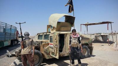 In this file photo taken on June 19, 2014, ISIL militants stand with a captured Iraqi army Humvee at a checkpoint outside Beiji refinery, some 250 kilometers north of Baghdad, Iraq. In mid-November, Shiite general Abdul-Wahab Al Saadi's forces successfully recaptured the oil refinery city of Beiji from the militants. AP Photo