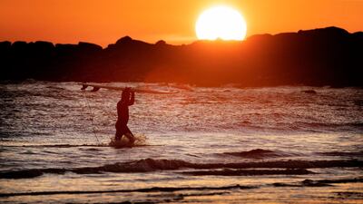 A surfer at Tynemouth beach in North Tyneside, UK, braves the low temperatures. PA via AP