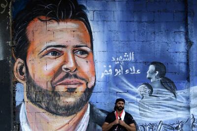 Ghayath al-Rawbeh, a Palestinian refugee who fled the Syrian crisis, poses on November 14, 2019 in front of a mural he painted of late Lebanese protester Alaa Abou Fakhr. AFP