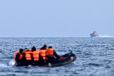 A Royal National Lifeboat Institution vessel approaches migrants in an inflatable boat crossing the English Channel, bound for Dover on the south coast of England. AFP
