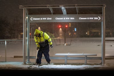 A maintenance worker clears snow from a bus stop as Winter Storm Fern arrives in Oklahoma. Reuters