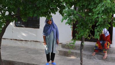 A female patient looks on as she stands next to an entrance outside of her ward.