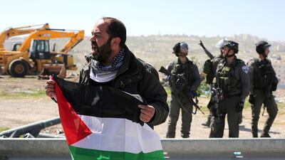 A Palestinian man takes part in a demonstration in the West Bank town of Abu Dis on March 6, 2015 against Palestinian land confiscation, as Israeli secrity forces stand guard. Abbas Momani/AFP Photo