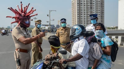 Police inspector Rajesh Babu wearing coronavirus-themed helmet speaks to a family on a motorbike at a checkpoint during a government-imposed nationwide lockdown as a preventive measure against the COVID-19 coronavirus in Chennai. AFP