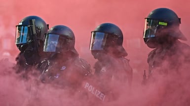 Anti-riot police walk through red smoke from a smoke bomb, during a demonstration by a 'No-G7' coalition in Geneva, Switzerland. AFP