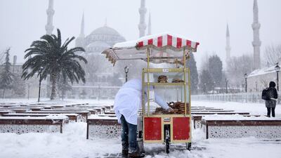 A vendor selling traditional Turkish simit (bread) waits for customers during snowfall in the historic Sultanahmet district in Istanbul. Mert Akyol / Depo Photos via AP