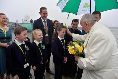 Pope Francis receives flowers from children after arriving in Knock. Vatican Media via Reuters