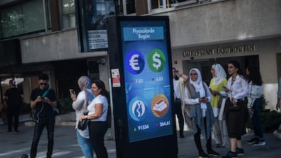 People stand next to a digital billboard giving updates on currencies and the Turkish stock exchange in Istanbul. AFP