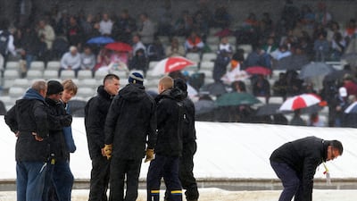 As the rain began to cease a little, ground staff stood by the pitch cover. The areas around proved too wet for an immediate start. Sang Tan / AP Photo