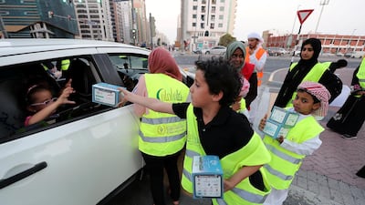 Ramadan Aman participant Iyad hands an iftar box to a passenger near Al Wahda Mall in Abu Dhabi. Pawan Singh / The National