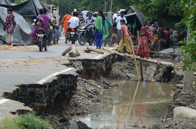 Indian villagers walks past a washed away section of road at Palsa village in Purnia district in Bihar state on August 18, 2017. Diptendu Dutta / AFP
