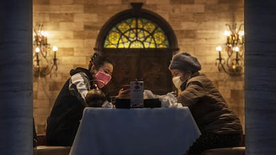 Chinese women wear protective masks as they eat dinner at an open restaurant in Beijing, China. Getty
