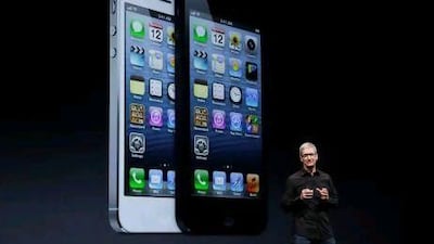 Apple CEO Tim Cook speaks in front of an image of the iPhone 5 during an Apple event in San Francisco.