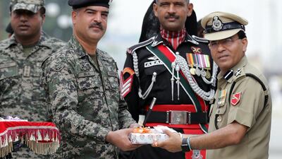 An Indian border security force commandant offers a box of sweets to Pakistan soldiers during independence day celebrations at a joint check post. Raminder Singh / EPA