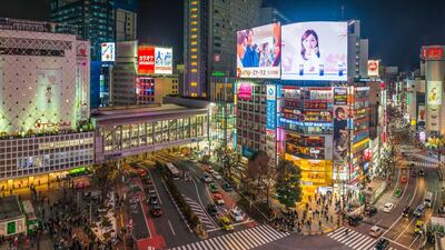 The iconic neon signs of Shibuya Crossing illuminate the crowds of commuters and shoppers below in the heart of Tokyo. Getty Images