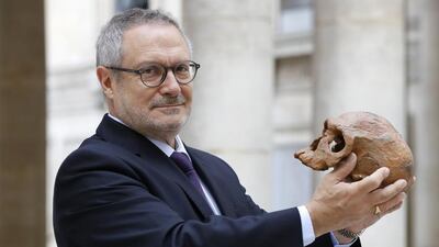 French paleoanthropologist Jean-Jacques Hublin poses on June 6, 2017 in Paris with the cast of a skull of Homo Sapiens discovered in Morocco on June 6, 2017. The ground-breaking discovery of fossils in Morocco show that Homo Sapiens was roaming Africa 300,000 yeas ago - 100,000 years longer than was previously believed. Patrick Kovarik / AFP